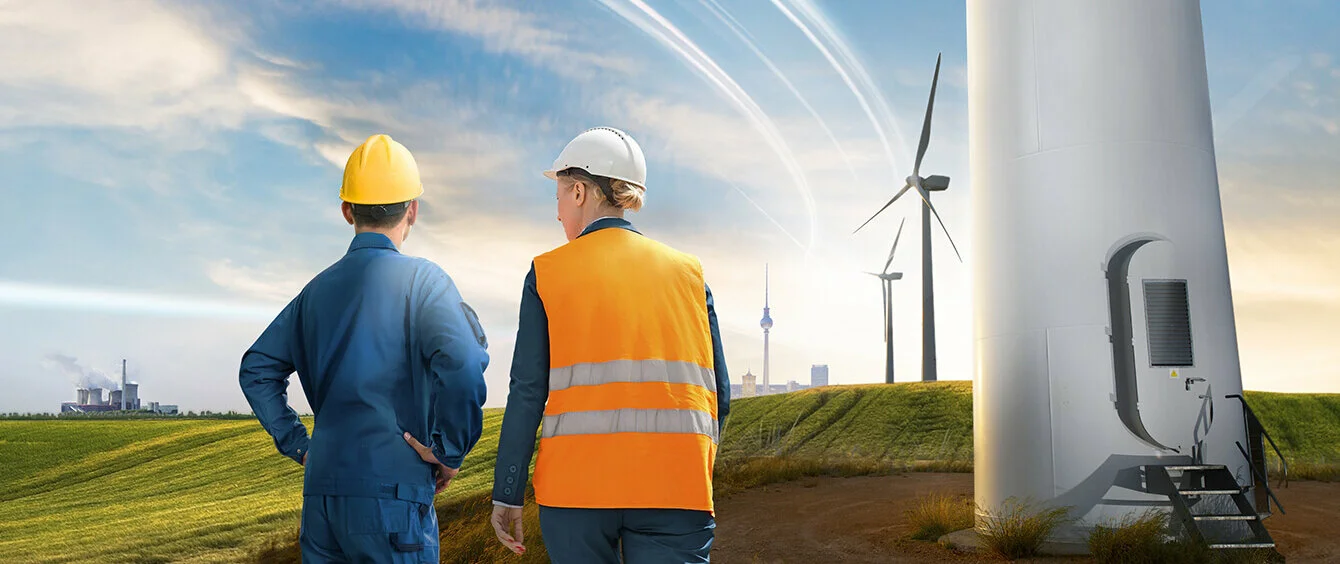 enformer Stimmungsbild Rückenansicht Arbeitende mit Blick auf Landschaft neben Fuß von Windkraftanlage Kraftwerke im Hintergund