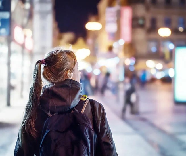 Mädchen von hinten in einer Stadt am Abend 