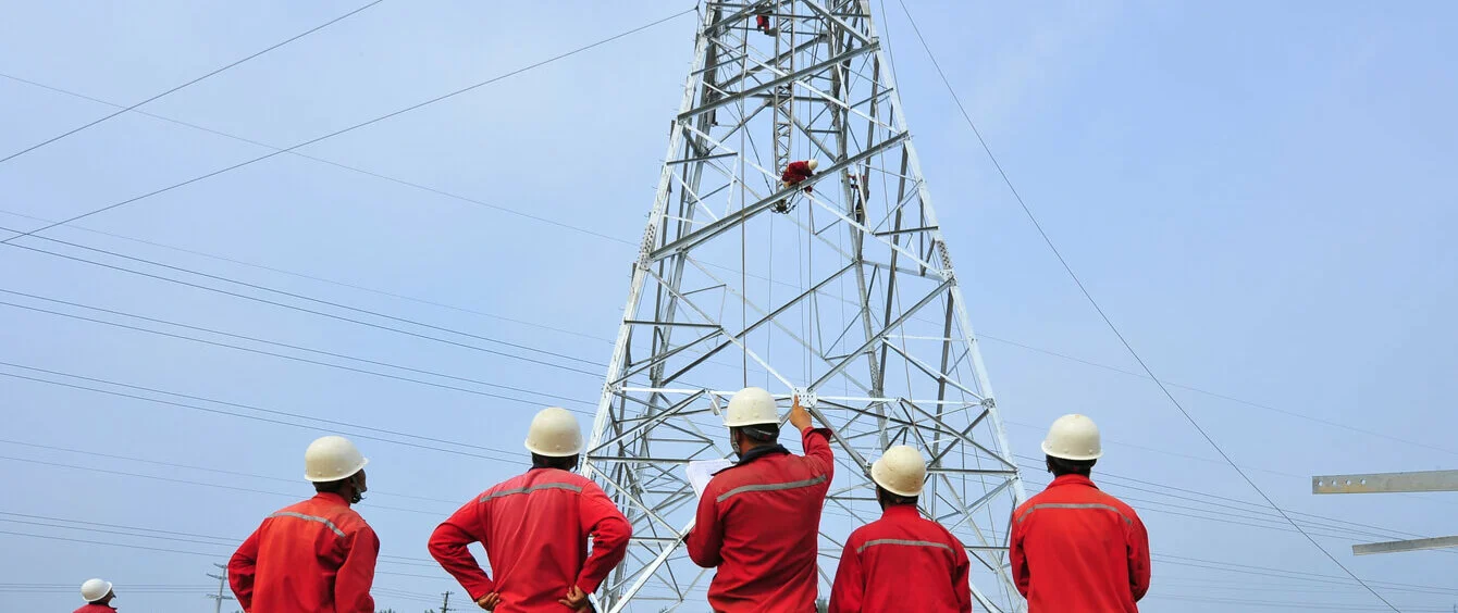 Energiewende im enformer Rückenansicht Arbeiter bei Konstruktion eines Strommasten