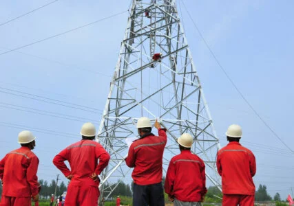 Energiewende im enformer Rückenansicht Arbeiter bei Konstruktion eines Strommasten