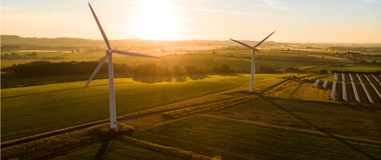 Stimmungsbild Drohnenaufnahme Windkraftanlagen und Solarpanels auf Feldern bei Sonnenaufgang