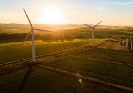 Stimmungsbild Drohnenaufnahme Windkraftanlagen und Solarpanels auf Feldern bei Sonnenaufgang
