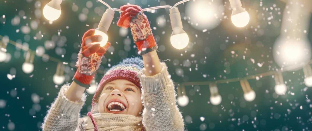 Stimmungsbild lachendes Kind mit Lichterkette bei Schnee