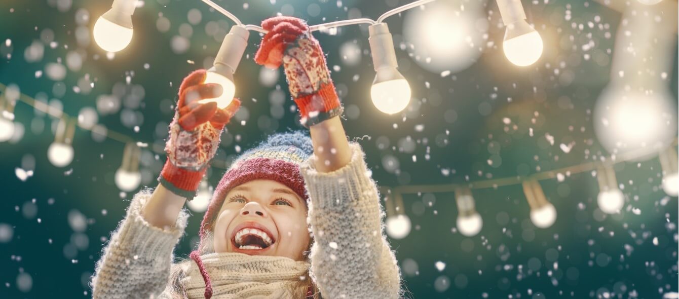 Stimmungsbild lachendes Kind mit Lichterkette bei Schnee