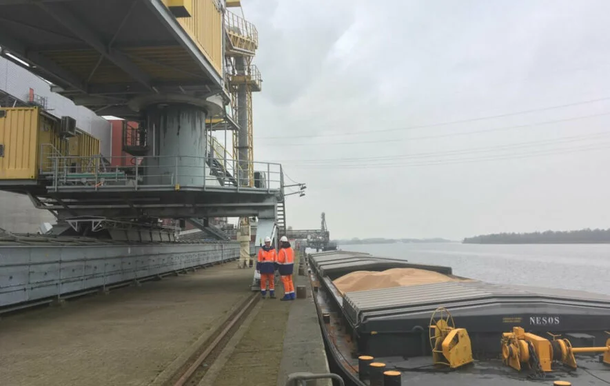 Energiewende im enformer Arbeiter neben Frachtschiff mit Holzpellets am Kai des Kraftwerks Amer