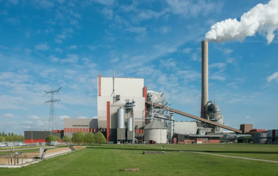 Aufnahme Kraftwerk Amer für Biomasse und Steinkohle vor grüner Wiese mit rauchendem Schornstein