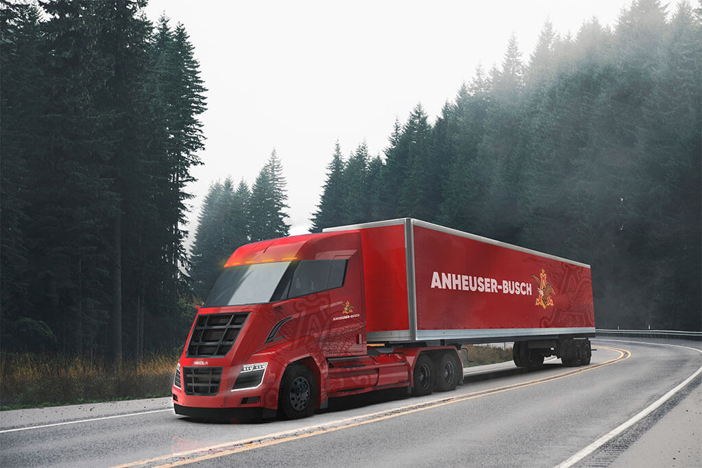Roter Nikola Truck auf kurviger Fahrbahn bei Nebel vor Tannenwald