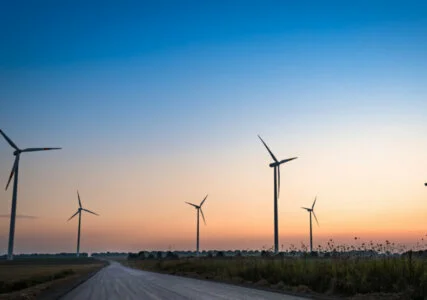 Windräder links und rechts einer Straße bei untergehender Sonne