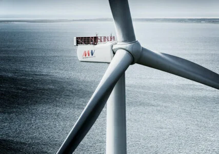 Rotorblätter einer Windkraftanlage in Nahaufnahme, im Hintergrund das Meer
