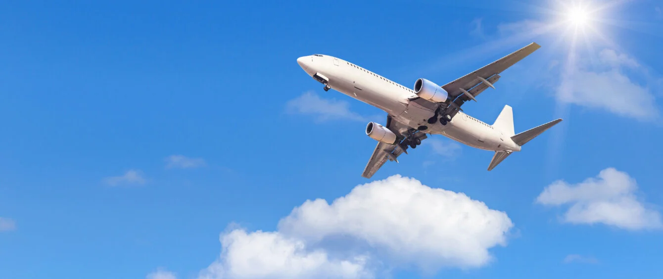 Zweistrahliges Verkehrsflugzeug fliegt vor der gleißenden Sonne her