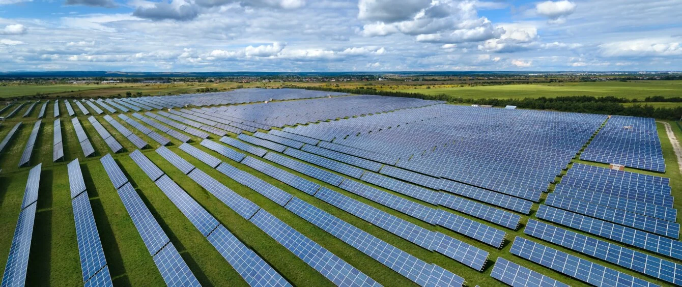 Das Bild zeigt einen Solarpark bei Sonnenschein.