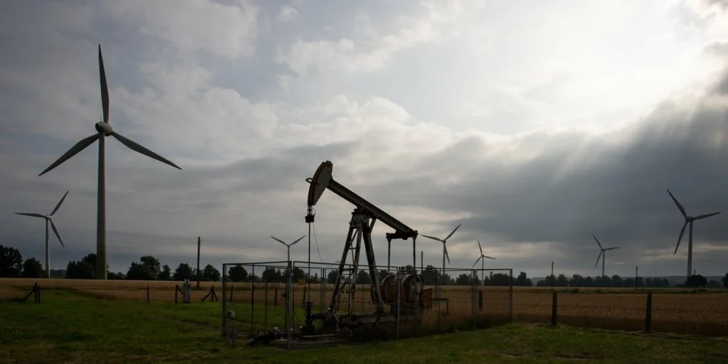 Ölsammelmaschinen vor modernen Windturbinen symbolisieren die Energiewende
